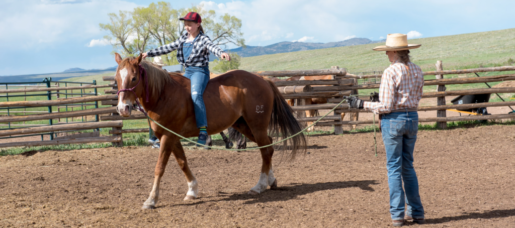 girl riding bareback on a horse being led by a cowgirl in the ring at Music Meadows Ranch
