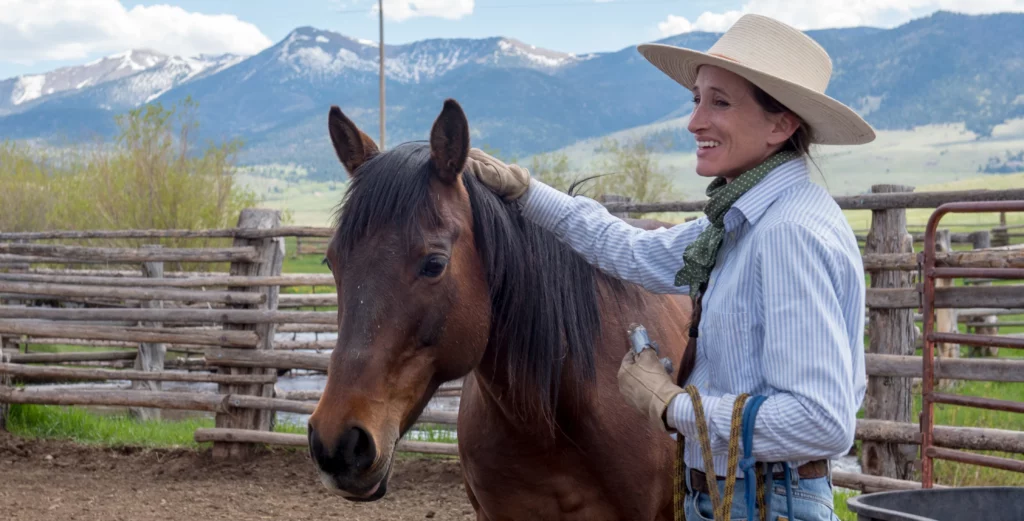 Smiling cowgirl petting a horse