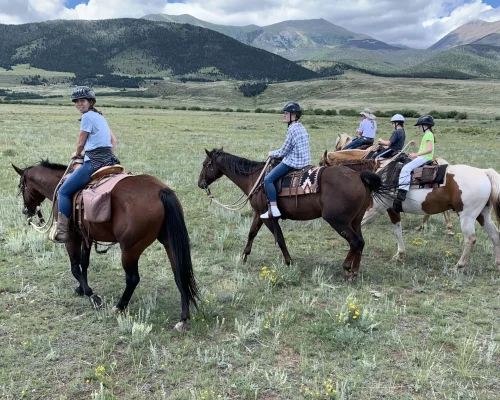 group of 5 guests of Music Meadows Ranch horseback riding across a field during a day at the ranch