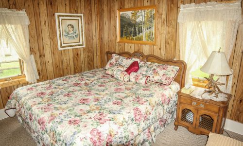 bedroom with floral comforter and wood paneled walls