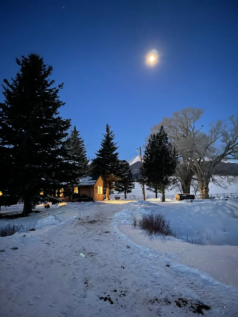 night view of the ranch house with a full moon and snow on the ground at Music Meadows Ranch